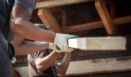 Worker holds a wooden board. Building a house.の写真素材