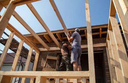 A worker measures a wooden workpiece with a meter. Building a house.