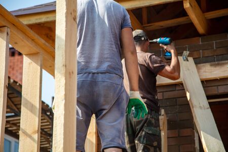 A worker measures a wooden workpiece with a meter. Building a house.の写真素材