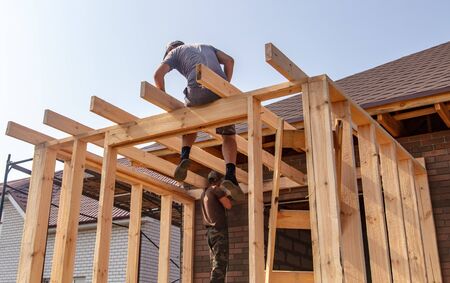 A worker measures a wooden workpiece with a meter. Building a house.の写真素材
