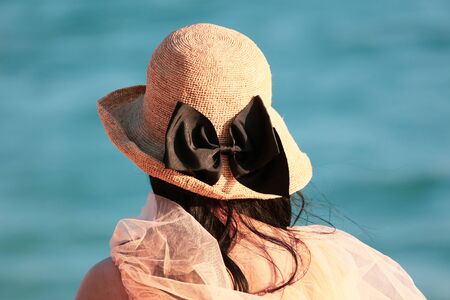 Girl in a straw hat on the beach by the sea.
