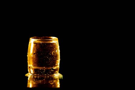 A glass of golden water is isolated on a black background.の写真素材