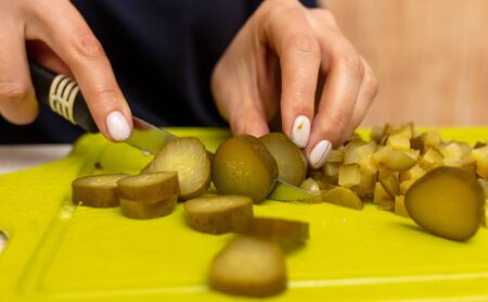 The girl cuts pickles with a knife on a plastic board.の写真素材
