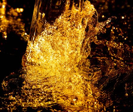Splashes and drops of golden water on a black background.の写真素材