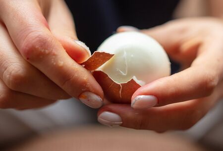The girl is cleaning a boiled egg. Cooking foodの写真素材