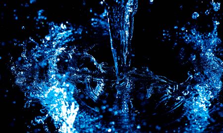 Splashes and drops of blue water on a black background.の写真素材
