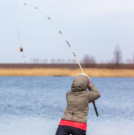 The girl catches fish in the lake for fishing rod. Early springの写真素材