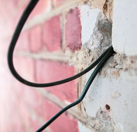 A worker lays an electric wire. Repair of the wall in the room.