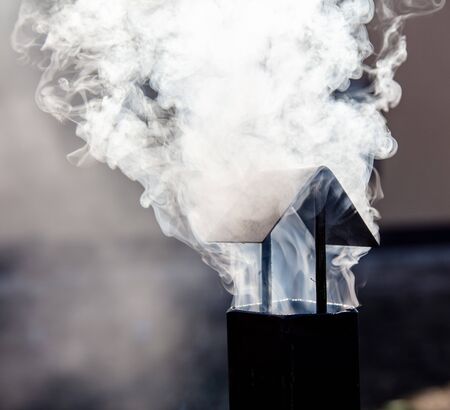 White smoke comes from a black metal pipe.の写真素材