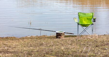 Table, chair and fishing rod on the shore of the pond. Inventory of the fishermanの写真素材