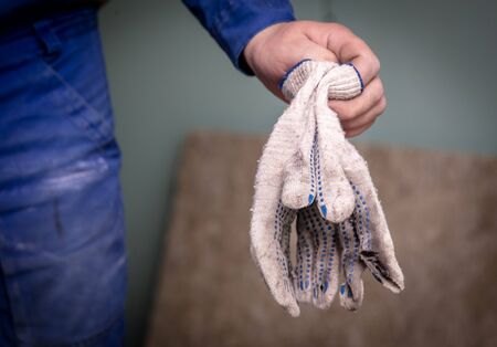 Worker holds construction gloves in his hand. Repair the room in the house.