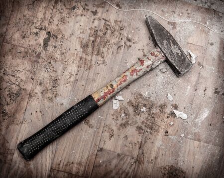 The hammer lies on the dirty floor. Repair of the room in the house.