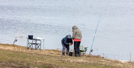 Mom and son are fishing in the lake for fishing rod. Early springの写真素材