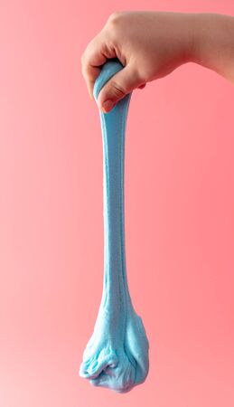 Blue slime in hand on a pink background. Jelly-like material for children to playの写真素材
