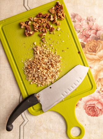 Knife-chopped walnuts on a green plastic board. Cooking in the kitchen.の写真素材