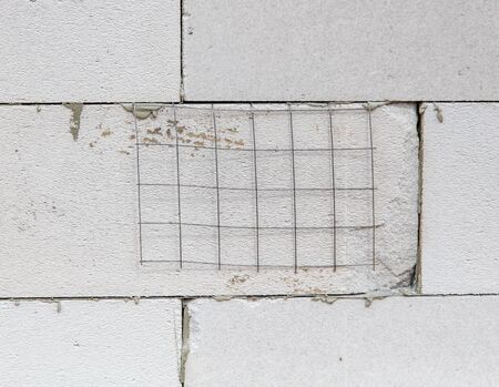 Metal mesh on the wall of foam concrete. Building a house.の写真素材