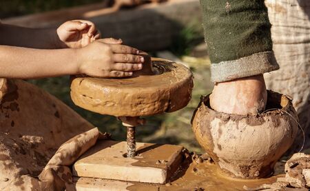 Hands of a boy and a man sculpt clay dishes. The ancient method of making dishes.の写真素材