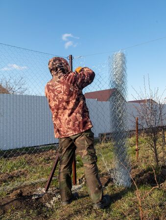 A man sets his hands a metal mesh on the fence.の写真素材