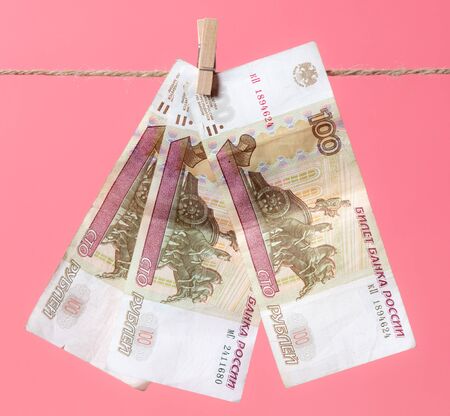 Rubles hang on a rope on a pink background.