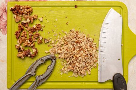 Knife-chopped walnuts on a green plastic board. Cooking in the kitchen.の写真素材