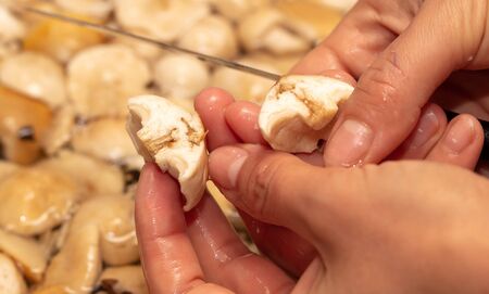 Girl cuts a knife with mushrooms in the kitchen.の写真素材