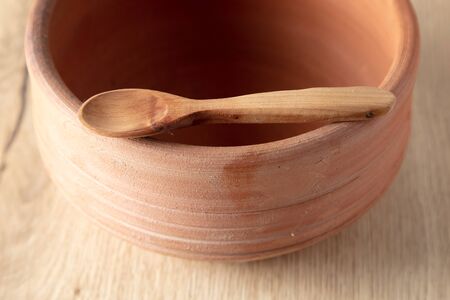 Wooden spoon on clay pot on a wooden background.の写真素材