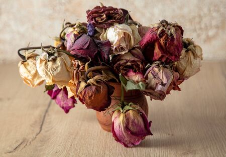 Dry rose flower on a wooden table.