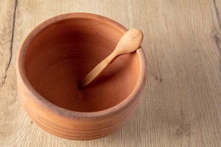 Wooden spoon on clay pot on a wooden background.の写真素材