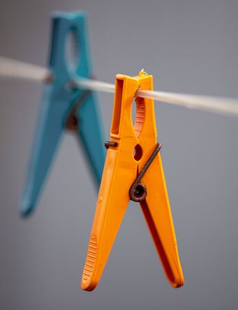 A plastic clothespin hangs on a clothesline.の写真素材