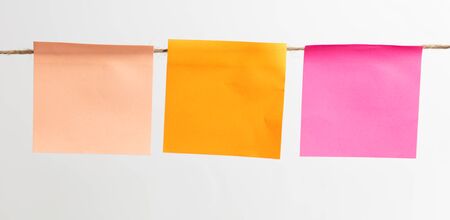 Colored papers hang on a rope on a white background.の写真素材