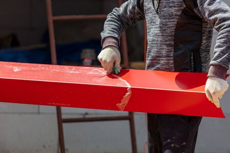 Workers install red metal tiles on the roof of the house.の写真素材