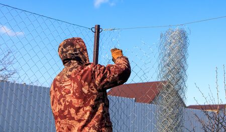 A man sets his hands a metal mesh on the fence.の写真素材