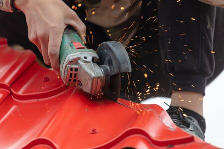 A worker cuts a red metal tile for a house roof.の写真素材