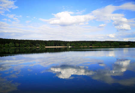Clouds on a blue sky with reflection in water at a pond.の写真素材