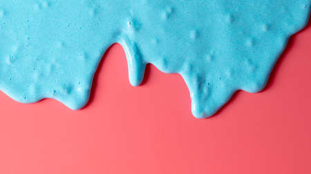 Blue slime isolated on pink background. Jelly-like material for children to playの写真素材