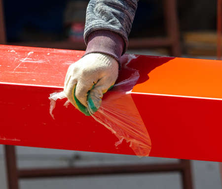 Workers install red metal tiles on the roof of the house.