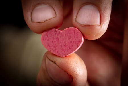Close-up of a pink heart in a man's hand.