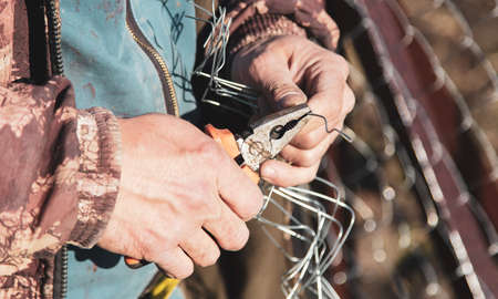 A man sets his hands a metal mesh on the fence.の写真素材