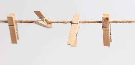Clothespins hang on a rope on a white background.