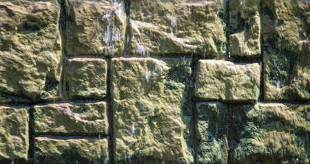 Water flows along a brick wall. Background