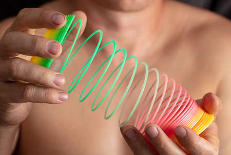 Close-up of a multi-colored slinky spring in a man's hand.のeditorial素材