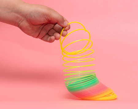 Rainbow spring in a hand on a pink background. Children toyのeditorial素材