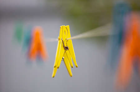A plastic clothespin hangs on a clothesline.の写真素材