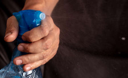 Close up of a blue spray bottle of spray gun in a man's hand.の写真素材