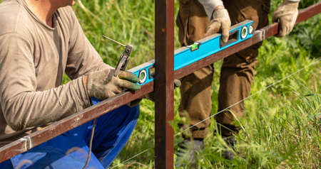 Worker installs a metal fence in the summer.