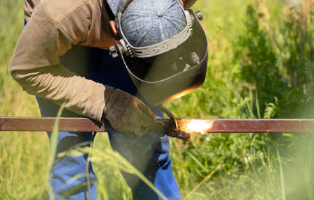 Worker installs a metal fence in the summer. Welding