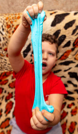 The boy is playing with a blue slime in his hands.の写真素材