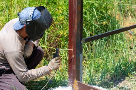 A worker welds metal for a fence. Technology