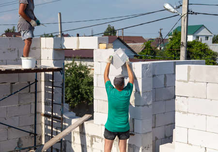 A worker builds the walls of a house from aerated concrete bricks. Technology
