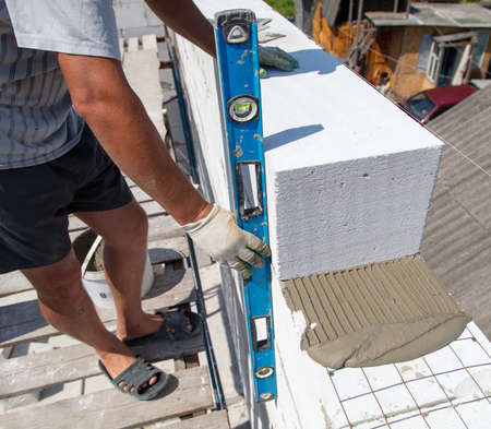 A worker builds the walls of a house from aerated concrete bricks. Technology